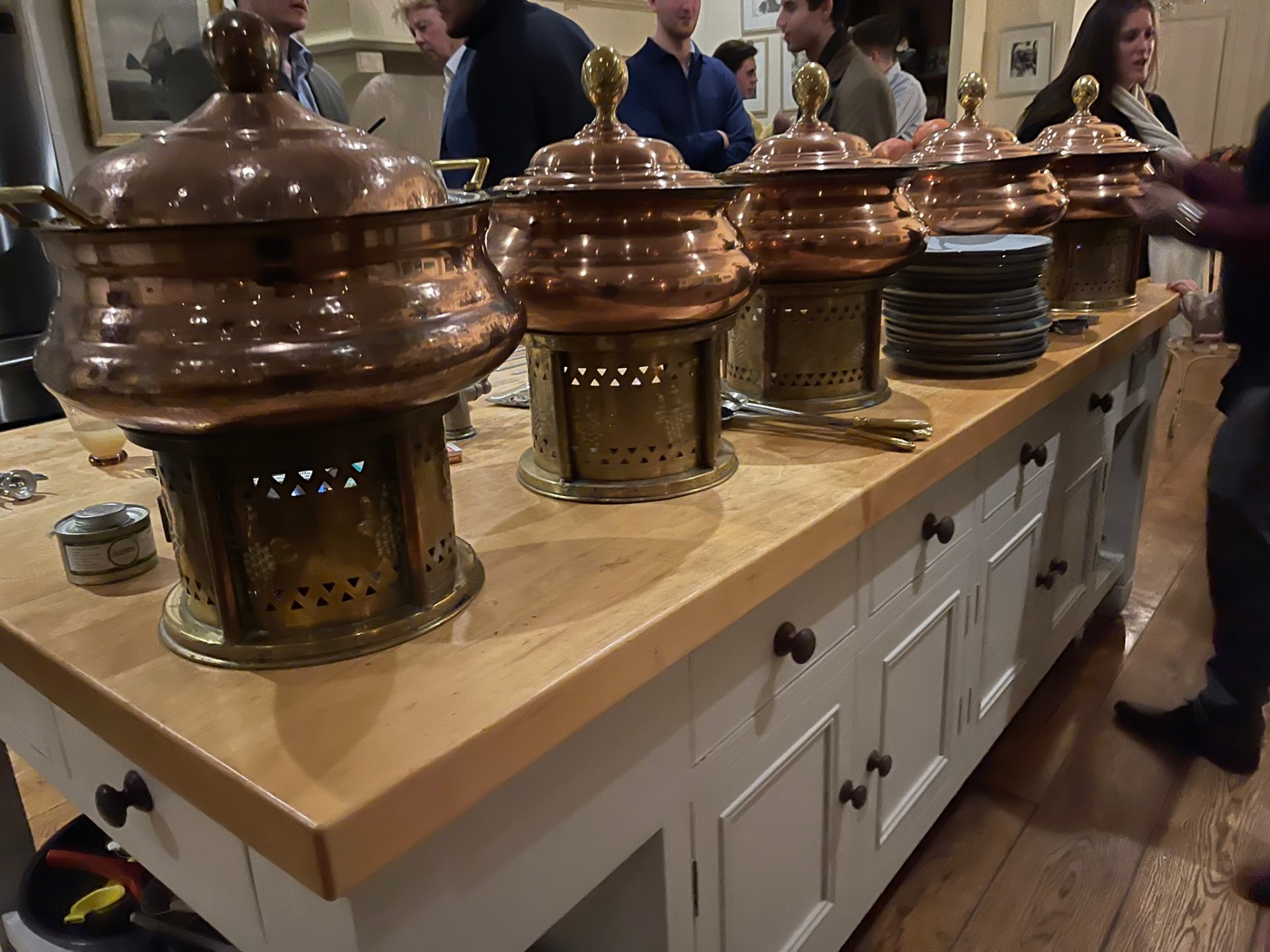 Guests being served from a line of copper chafing dishes at an evening dinner event.