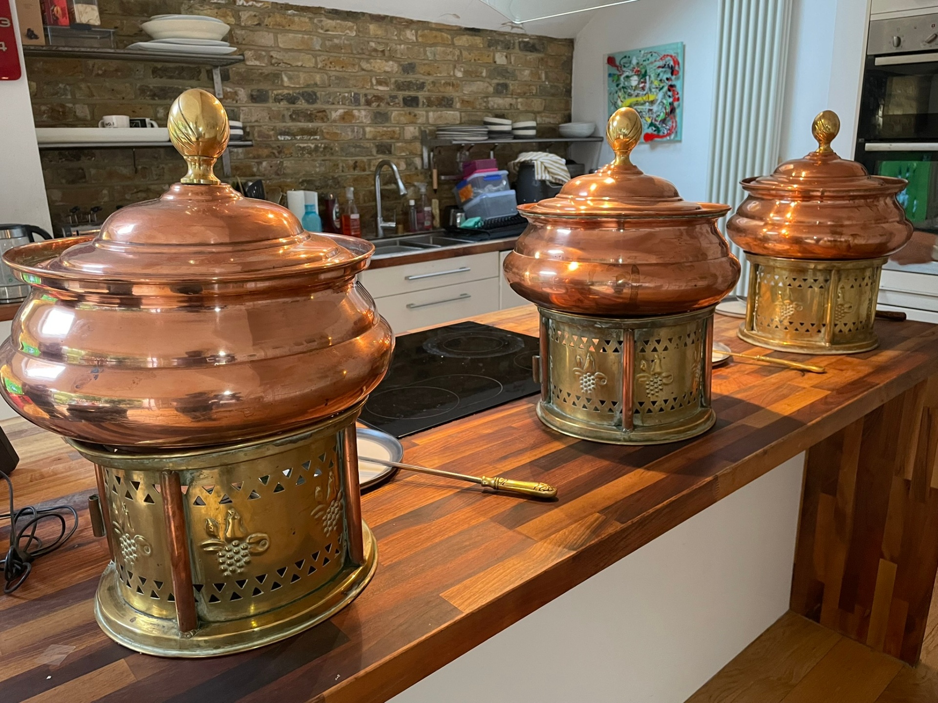 Three hand-polished copper and brass chafing units on a wooden counter, ready for service at a private Jaflong Catering event.